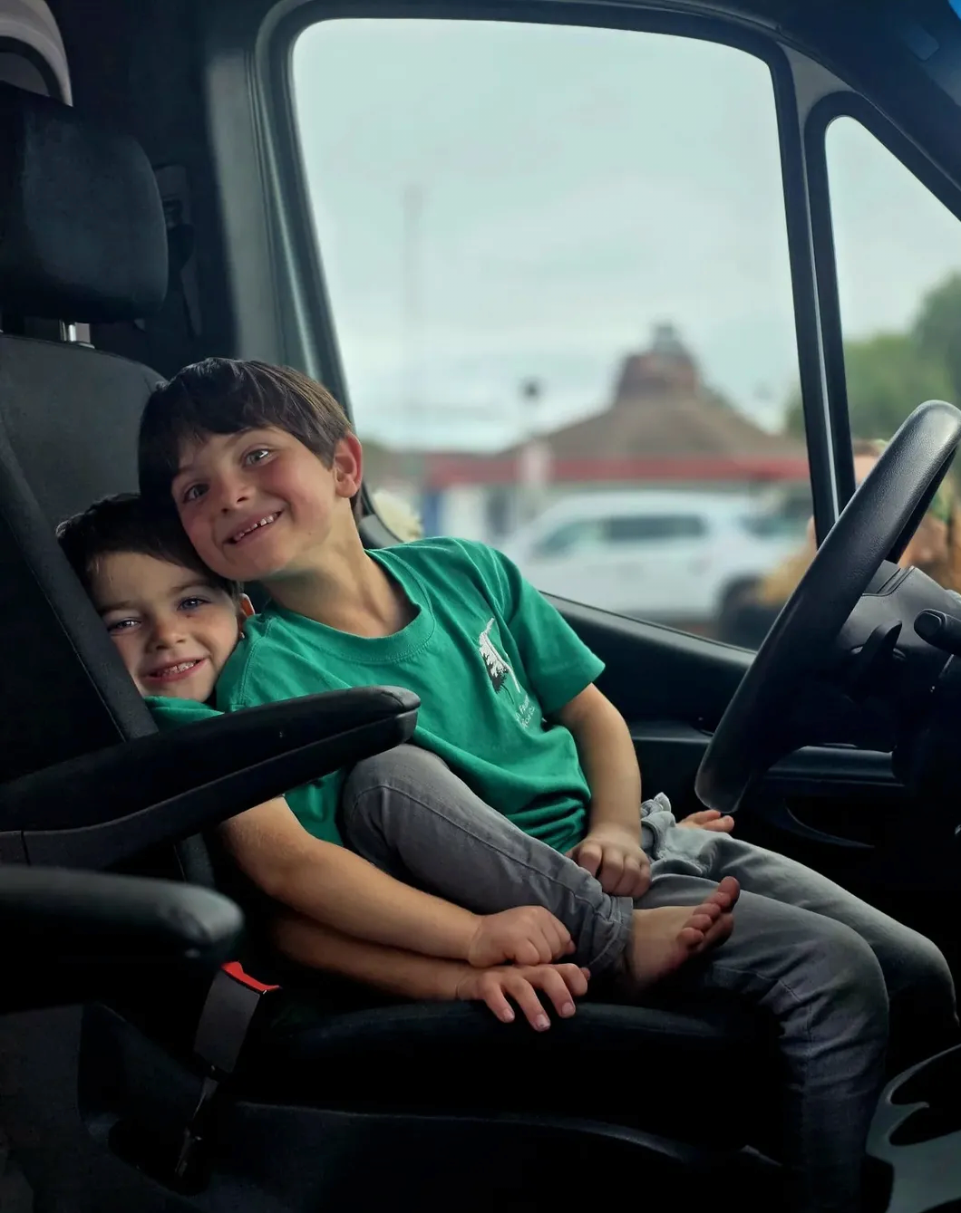 Erin Resch's boys smiling inside their Mercedes Sprinter van off-grid sustainability testing lab