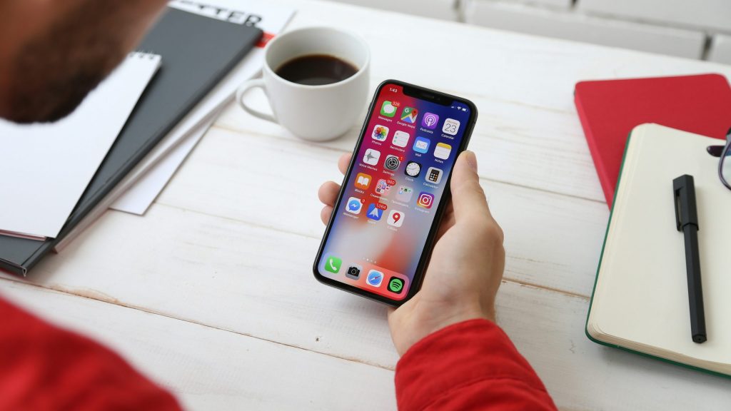 Top Recommended Eco-Friendly Apps text overlay on a white desk with an Apple Watch displaying the JouleBug app icon, glasses, and office supplies.