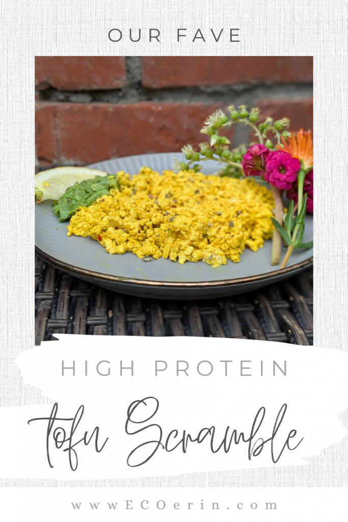 A vertical Pinterest pin design featuring a plate of high protein tofu scramble with flowers and avocado, with white paint-stroke text reading High Protein Tofu Scramble.