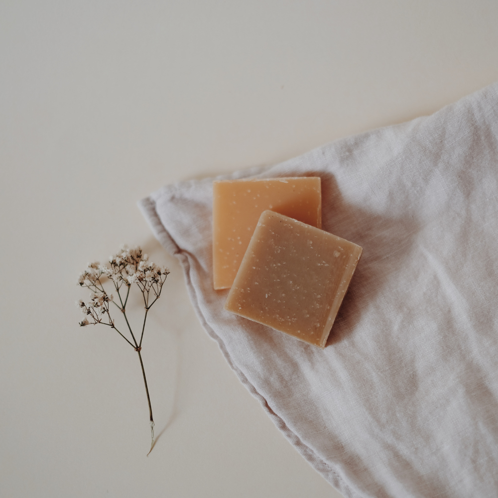 Zero-waste living guide for small spaces. Showcasing bar soap, shampoo, and conditioner bars in a small dish on a clean, minimal bathroom counter.
