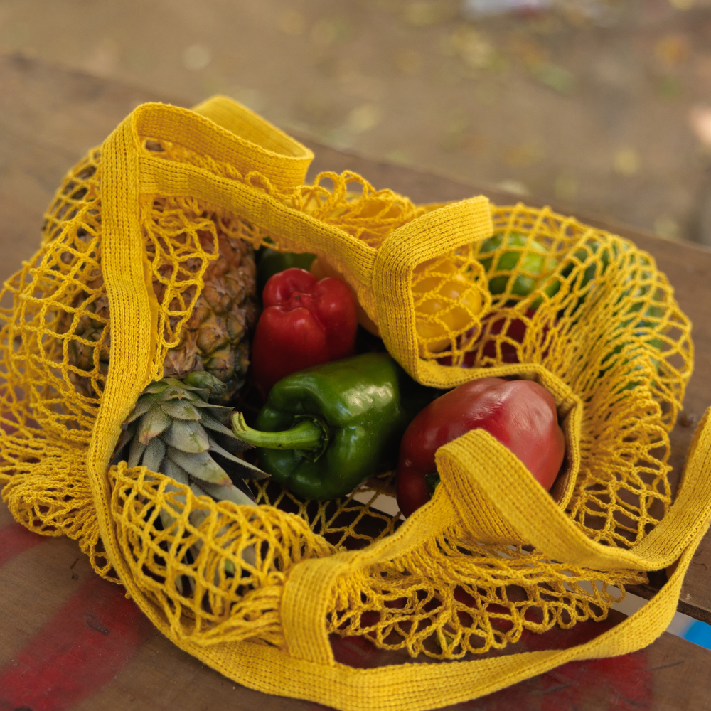 Yellow mesh reusable produce bags filled with fresh vegetables for zero waste grocery shopping.