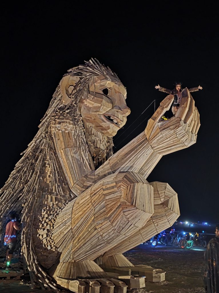 Image of Thomas Dampos troll art instillation with ECO Erin (Erin Resch) on top of the brown installation. 