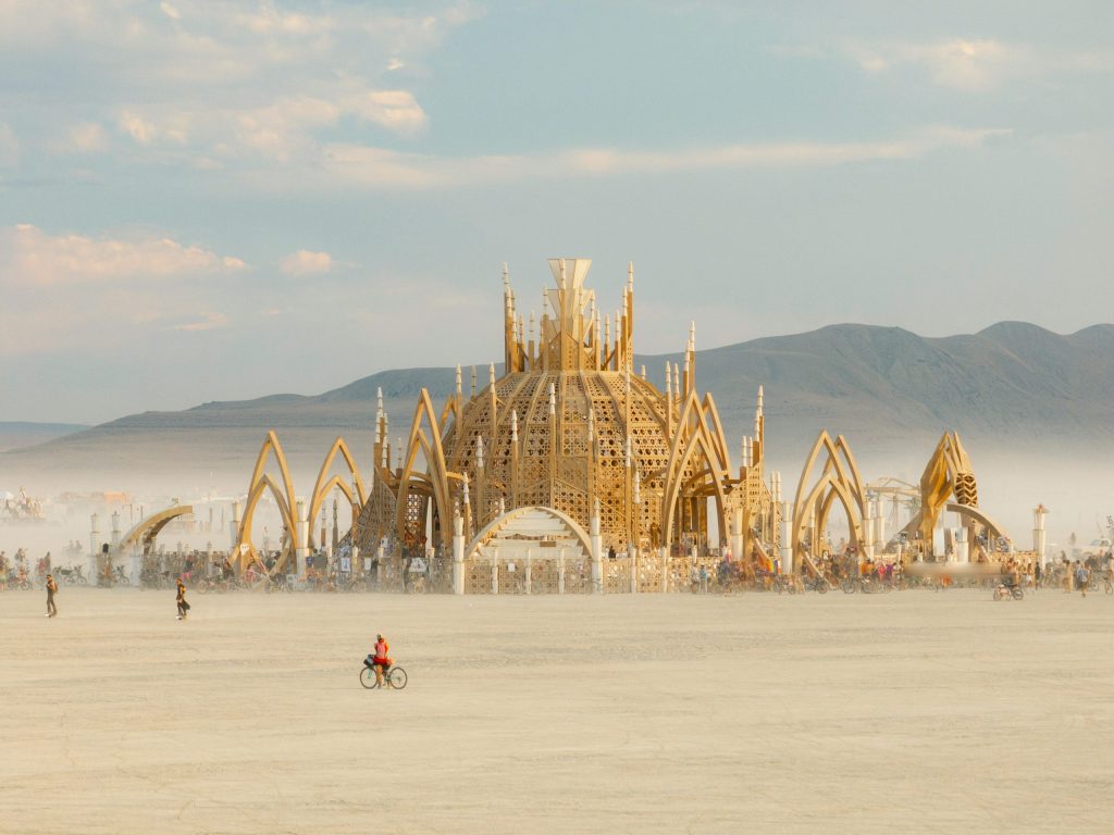 Burning Man sustainability showcased with an image of a temple built in the middle of the desert and afterwards is taken down with the burning man "leave no trace" principles. Image of a wooden temple in the middle of Black Rock City.